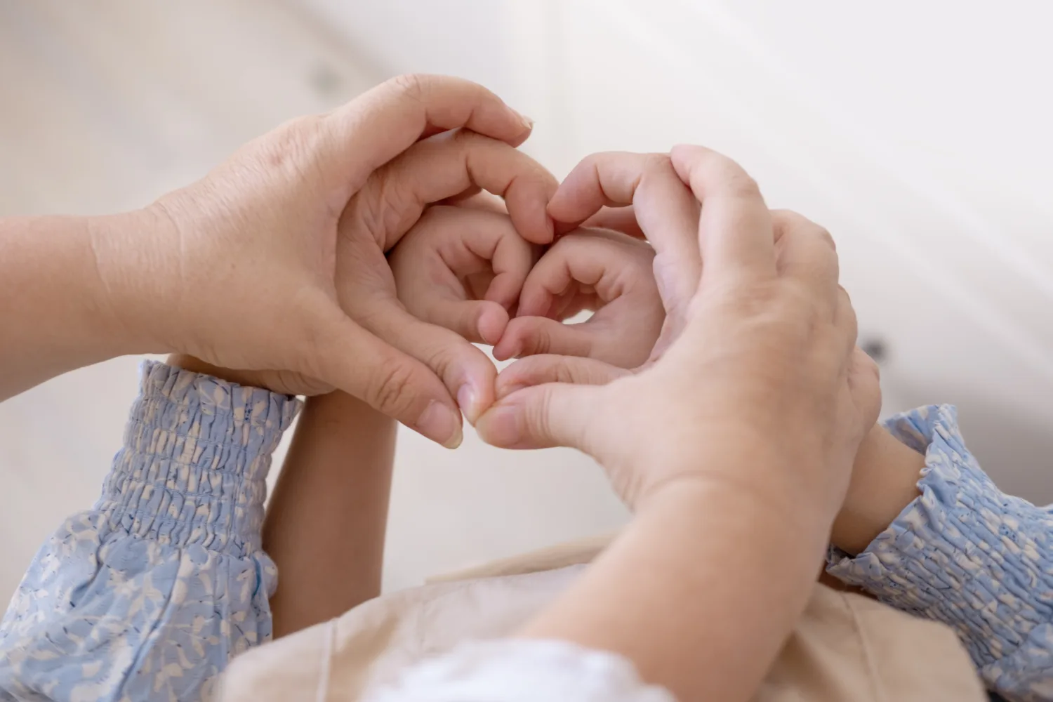 Grandmother, mother and daughter hands with heart shape, family unity, connection female generations, heartwarming image three generations women, feminine lineage