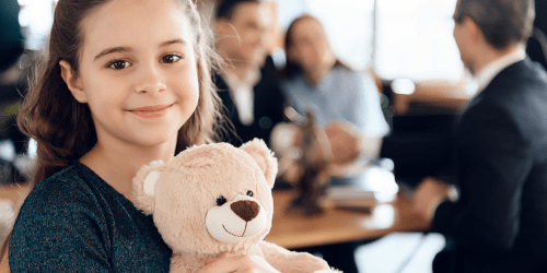 Smiling girl holding teddy bear during legal guardianship meeting