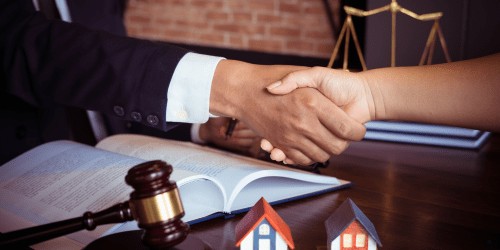 Handshake over legal contract with gavel and house models